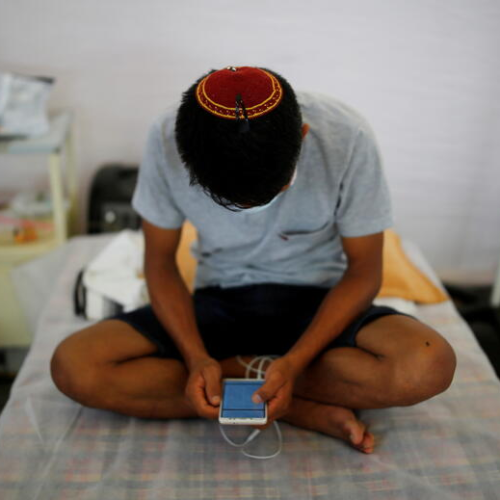 An Indian checks his mobile phone at a COVID-19 care facility in New Delhi.